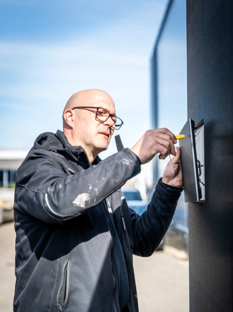 Een HOOQD specialist monteert een digital LED scherm